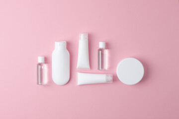 Cosmetic composition with cosmetic skin care products and on pink background. Flat lay, copy space