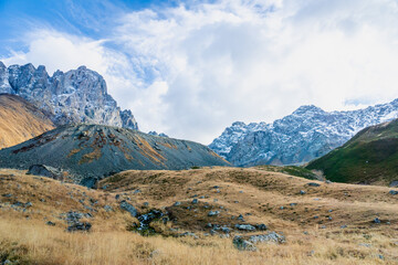 mountain landscape in Juta trekking area landscape with snowy mountains in sunny autumn day - popular hiking in the Caucasus mountains, Kazbegi region, Georgia.
