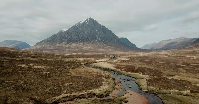 4k aerial footage of Buachaille Etive Mor mountain, River Coe, and A82 road. Scottish Highlands, UK. Panning backwards.