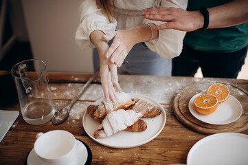 a girl and a guy are preparing croissants with a filling for breakfast close-up