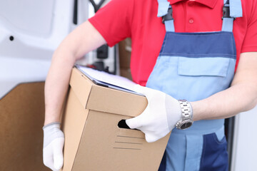 Male courier holds cardboard box with documents