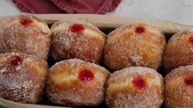 Camera movement. Berliners. Donuts with raspberry jam lie on a serving tray on a white plate, a donut with a flowing filling. Delicious sweet donuts. Making donuts with jam.