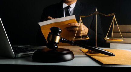 Justice and law concept.Male judge in a courtroom with the gavel, working with, computer and docking keyboard, eyeglasses, on table in morning light