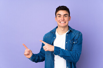 Teenager caucasian  handsome man isolated on purple background frightened and pointing to the side