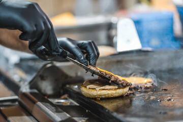 Fototapeta na wymiar Chef rotates hamburger patties on the grill with a spatula.