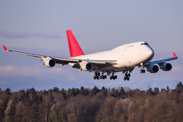 Widebody cargo aircraft landing in front of forest