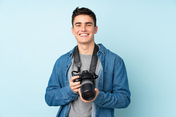 Teenager photographer man isolated on blue background - obrazy, fototapety, plakaty