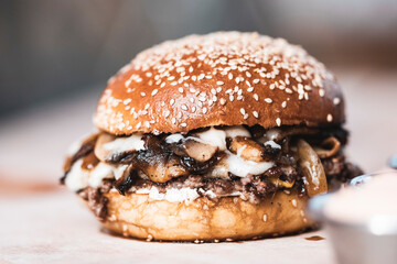 A delicious burger with mushroom slices looking very dense.