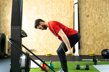 Sport man doing exercise in the skier's simulation machine in gym