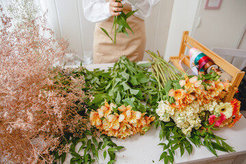 the florist's table is littered with fresh flowers before starting work. Florist in the background