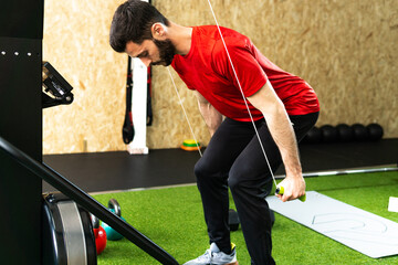 Sport man doing exercise in the skier's simulation machine in gym