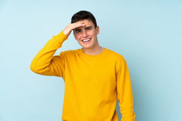 Teenager caucasian handsome man isolated on purple background looking far away with hand to look something