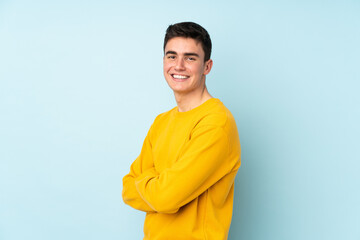 Teenager caucasian handsome man isolated on purple background with arms crossed and looking forward