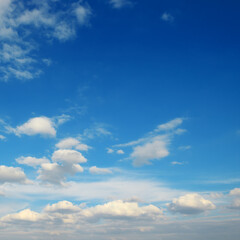 Fluffy clouds against bright azure sky.
