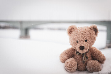 The toy bear was left in the winter at the children's playground