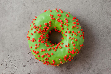 green donat with red crumbs on a gray background