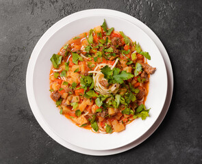 noodle with pasta, meat, sauce and herbs in a white plate on a dark background, Asian cuisine