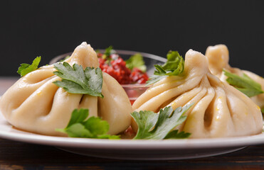 khinkali with tomato sauce, herbs on a dark , dumplings