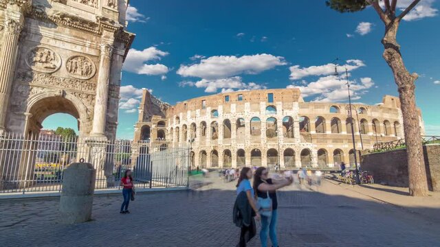 Many tourists visiting The Colosseum or Coliseum timelapse hyperlapse, also known as the Flavian Amphitheatre in Rome, Italy. Arch of Constantine. Blue sky at sunny day