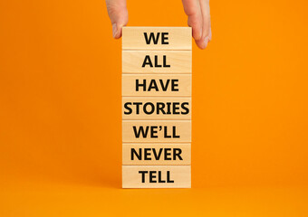 We all have stories we will never tell symbol. Blocks with words We all have stories we will never tell. Businessman hand. Beautiful orange background. Business, popular quotation concept. Copy space.