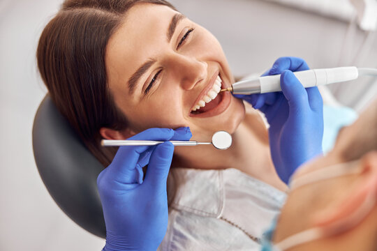 Female patient at dental procedure, doctor using dental instruments in modern dental clinic - Powered by Adobe
