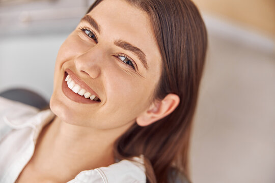 Attractive woman visiting dental clinic. Happy young woman sitting in dental chair at dentist office