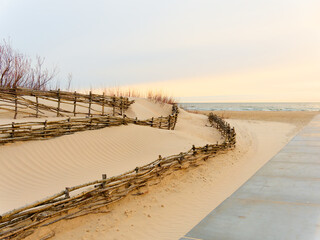 Drive through the dunes to the sea. Concrete road.