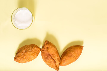 Tasty home made snack. Glass of milk with fried pies. Fried buns with milk on a yellow.