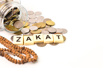 ZAKAT word with stack of coins and Islamic prayer beads over white background