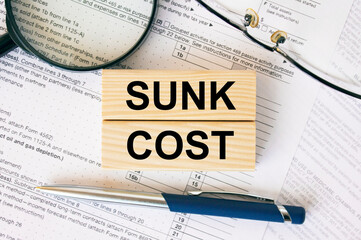 Wooden blocks with text Sunk Cost on financial docs