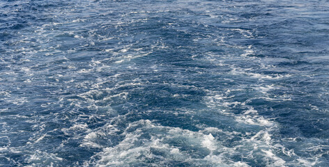 Turbulent flow of a boat wake. Sea wave. The yacht sails, leaving behind a trail and waves.