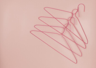 Metal pink hangers for clothes on pink background.  Empty cloth hanger template. Fashion blog,  sales,  store, online  shopping concept. 