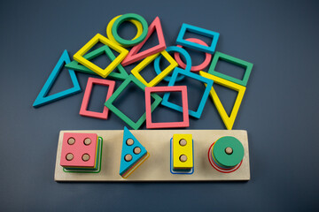 Multicolored wooden blocks on blue background. Trendy puzzle toys. Geometric shapes: square, circle, triangle, rectangle. Educational toys for kindergarten, preschool or daycare. Back to school	
