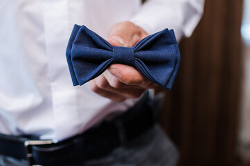 Blue bow tie in the hands of the groom. Bow tie in the hands of a man