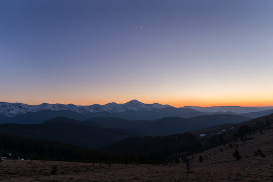 Panoramic view of snow melted Carpathian Mountains at evening twilight