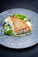 Modern style traditional fried skrei cod fish filet with mashed potatoes and baby broccoli served as close-up on ceramic design plate with copy space