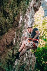 Young handsome sportsman climbing up a rock cliff