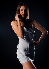 Young beautiful woman in a white dress on a grey background