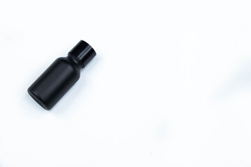 Glass bottle of hair care cream mixed with small black bamboo charcoal powder, placed on a white background.