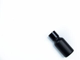 Glass bottle of hair care cream mixed with small black bamboo charcoal powder, placed on a white background.