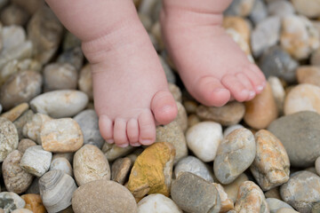 Two small bare feet of a little child standing on stones