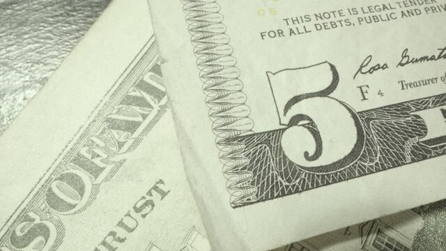 Macro extreme closeup detail of a US 5 dollar bill with five dollar printed in micro sized text  with saying "this note is legal tender for all debts, public and private" treasurer the united states