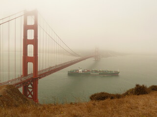 High viewpoint of Golden Gate Bridge in some fog with ship passing underneath
