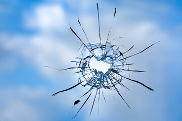 Cracks in the window glass on a background of sky.