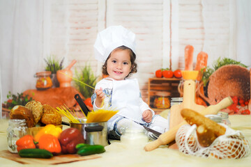 curly little girl chef in the kitchen wearing a chef's hat
