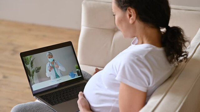 Distance medical help, online medical consultation. Pregnant woman talks with a female doctor by video call uses laptop, getting medical consultation, receives answers to questions and recommendations