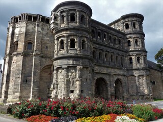 Römische Porta Nigra mit bunt blühenden Blumenrabatten in Trier an der Mosel