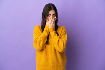 Young caucasian woman isolated on purple background covering mouth with hands