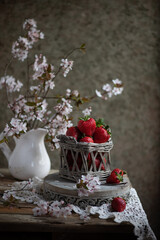 Strawberries in a small basket on the wooden table, vintage lifestyle. 