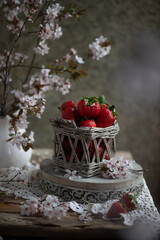 Strawberries in a small basket on the wooden table, vintage lifestyle. 